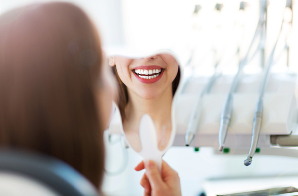 Woman looking at her smile in a mirror in New York, NY