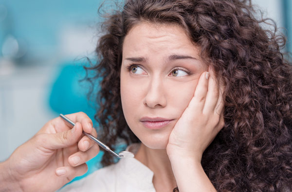 Woman holding cheek due to tooth ache in New York, NY